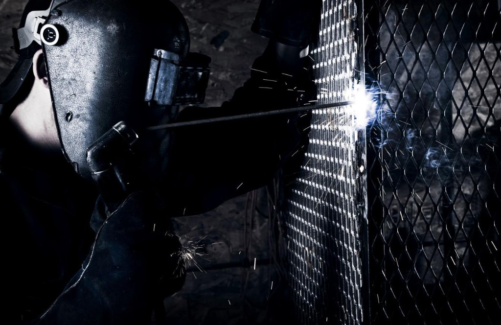 Soldador com capacete e equipamento de proteção em operação de solda